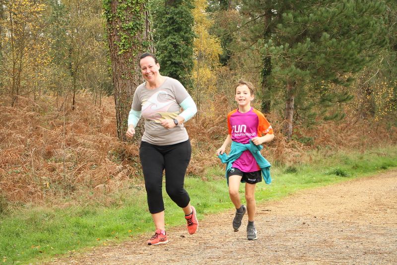 A parent and child running on a forest trail